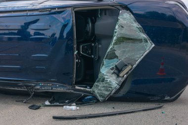 Kaza hasarı: yolda devrilmiş bir arabanın görüntüsü. Devrilen araba yan yatar. Çarpışma sonrası oluşmuş. Detaylar, yakın plan. Kazalar, sigorta ve güvenlik konuları.