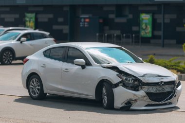 Ön tarafı ezilmiş bir araba, trafik kazasında hasar görmüş. Trafik kazası: çarpışma belirtileri olan bir araba. Çekilmeyi ya da onarılmayı bekliyor. Deforme olmuş kapüşonlu ve ön tamponlu bir araba..