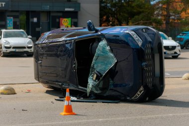 Kaza hasarı: yolda devrilmiş bir arabanın görüntüsü. Devrilen araba yan yatar. Çarpışma sonrası oluşmuş. Detaylar, yakın plan. Kazalar, sigorta ve güvenlik konuları.