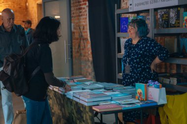 Kitapçıya ya ya da kitap fuarına gelip kitap seçiyor. Alışveriş ve okuma. Kütüphane. Kitap festivali. Kültürel etkinlik.