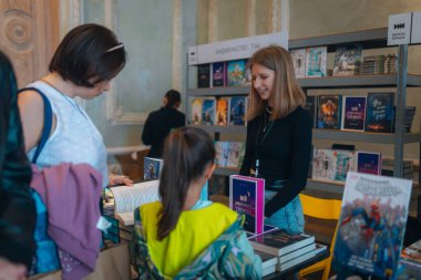 Kitapçıya ya ya da kitap fuarına gelip kitap seçiyor. Alışveriş ve okuma. Kütüphane. Kitap festivali. Kültürel etkinlik.