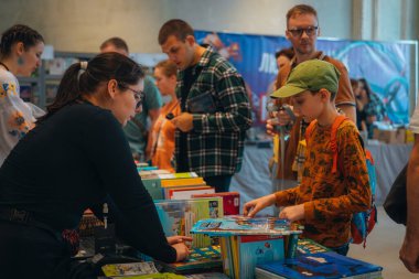 Kitapçıya ya ya da kitap fuarına gelip kitap seçiyor. Alışveriş ve okuma. Kütüphane. Kitap festivali. Kültürel etkinlik.