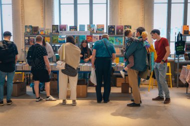 Kitapçıya ya ya da kitap fuarına gelip kitap seçiyor. Alışveriş ve okuma. Kütüphane. Kitap festivali. Kültürel etkinlik.