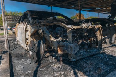 Kül ve çamur kaplı yanmış cesetlerde bükülmüş metal ve erimiş yapılar görülüyor. Arabanın içi mahvolmuş. Askeri çatışma ve bombardıman sonucu. Yıkılmış otopark.