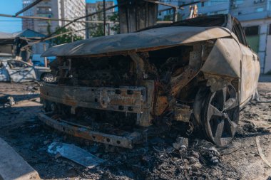 Kül ve çamur kaplı yanmış cesetlerde bükülmüş metal ve erimiş yapılar görülüyor. Arabanın içi mahvolmuş. Askeri çatışma ve bombardıman sonucu. Yıkılmış otopark.