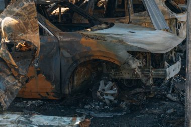 Kül ve çamur kaplı yanmış cesetlerde bükülmüş metal ve erimiş yapılar görülüyor. Arabanın içi mahvolmuş. Askeri çatışma ve bombardıman sonucu. Yıkılmış otopark.