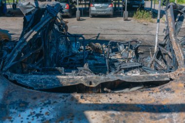 Kül ve çamur kaplı yanmış cesetlerde bükülmüş metal ve erimiş yapılar görülüyor. Arabanın içi mahvolmuş. Askeri çatışma ve bombardıman sonucu. Yıkılmış otopark.