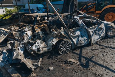 Kül ve çamur kaplı yanmış cesetlerde bükülmüş metal ve erimiş yapılar görülüyor. Arabanın içi mahvolmuş. Askeri çatışma ve bombardıman sonucu. Yıkılmış otopark.