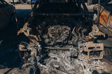 Kül ve çamur kaplı yanmış cesetlerde bükülmüş metal ve erimiş yapılar görülüyor. Arabanın içi mahvolmuş. Askeri çatışma ve bombardıman sonucu. Yıkılmış otopark.