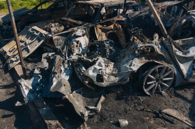 Kül ve çamur kaplı yanmış cesetlerde bükülmüş metal ve erimiş yapılar görülüyor. Arabanın içi mahvolmuş. Askeri çatışma ve bombardıman sonucu. Yıkılmış otopark.