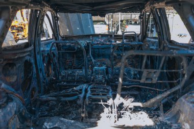 Kül ve çamur kaplı yanmış cesetlerde bükülmüş metal ve erimiş yapılar görülüyor. Arabanın içi mahvolmuş. Askeri çatışma ve bombardıman sonucu. Yıkılmış otopark.