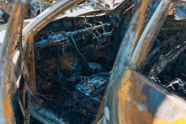 Kül ve çamur kaplı yanmış cesetlerde bükülmüş metal ve erimiş yapılar görülüyor. Arabanın içi mahvolmuş. Askeri çatışma ve bombardıman sonucu. Yıkılmış otopark.