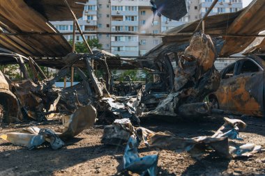 Kül ve çamur kaplı yanmış cesetlerde bükülmüş metal ve erimiş yapılar görülüyor. Arabanın içi mahvolmuş. Askeri çatışma ve bombardıman sonucu. Yıkılmış otopark.