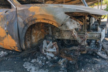 Kül ve çamur kaplı yanmış cesetlerde bükülmüş metal ve erimiş yapılar görülüyor. Arabanın içi mahvolmuş. Askeri çatışma ve bombardıman sonucu. Yıkılmış otopark.