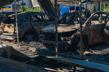 Kül ve çamur kaplı yanmış cesetlerde bükülmüş metal ve erimiş yapılar görülüyor. Arabanın içi mahvolmuş. Askeri çatışma ve bombardıman sonucu. Yıkılmış otopark.