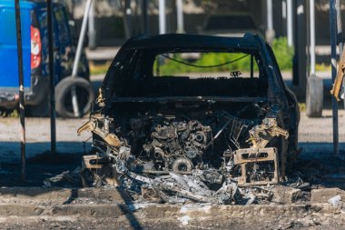 Kül ve çamur kaplı yanmış cesetlerde bükülmüş metal ve erimiş yapılar görülüyor. Arabanın içi mahvolmuş. Askeri çatışma ve bombardıman sonucu. Yıkılmış otopark.