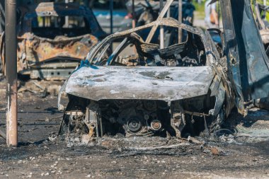 Kül ve çamur kaplı yanmış cesetlerde bükülmüş metal ve erimiş yapılar görülüyor. Arabanın içi mahvolmuş. Askeri çatışma ve bombardıman sonucu. Yıkılmış otopark.