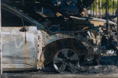 Kül ve çamur kaplı yanmış cesetlerde bükülmüş metal ve erimiş yapılar görülüyor. Arabanın içi mahvolmuş. Askeri çatışma ve bombardıman sonucu. Yıkılmış otopark.