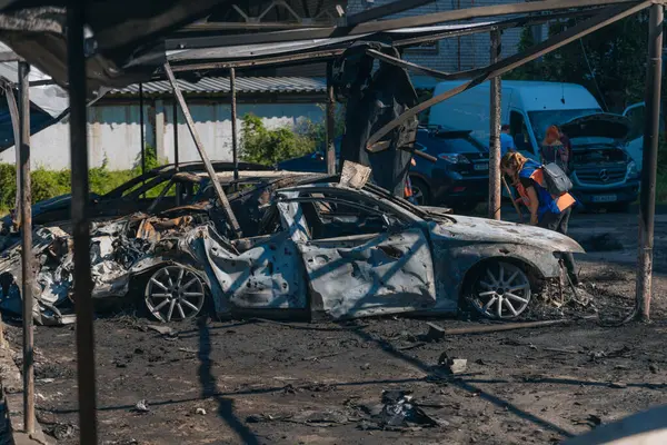 Kül ve çamur kaplı yanmış cesetlerde bükülmüş metal ve erimiş yapılar görülüyor. Arabanın içi mahvolmuş. Askeri çatışma ve bombardıman sonucu. Yıkılmış otopark.