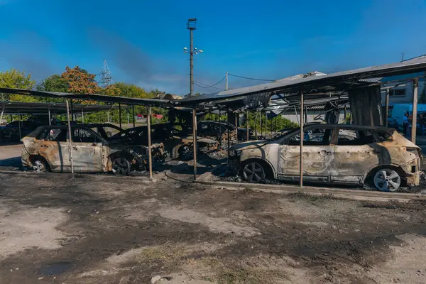 Kül ve çamur kaplı yanmış cesetlerde bükülmüş metal ve erimiş yapılar görülüyor. Arabanın içi mahvolmuş. Askeri çatışma ve bombardıman sonucu. Yıkılmış otopark.