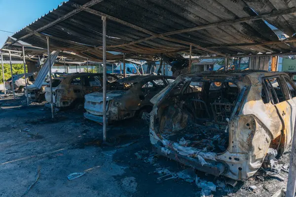 Kül ve çamur kaplı yanmış cesetlerde bükülmüş metal ve erimiş yapılar görülüyor. Arabanın içi mahvolmuş. Askeri çatışma ve bombardıman sonucu. Yıkılmış otopark.