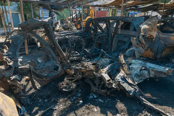 Kül ve çamur kaplı yanmış cesetlerde bükülmüş metal ve erimiş yapılar görülüyor. Arabanın içi mahvolmuş. Askeri çatışma ve bombardıman sonucu. Yıkılmış otopark.