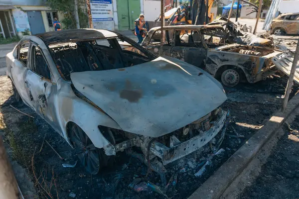 Kül ve çamur kaplı yanmış cesetlerde bükülmüş metal ve erimiş yapılar görülüyor. Arabanın içi mahvolmuş. Askeri çatışma ve bombardıman sonucu. Yıkılmış otopark.