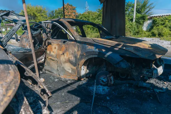 Kül ve çamur kaplı yanmış cesetlerde bükülmüş metal ve erimiş yapılar görülüyor. Arabanın içi mahvolmuş. Askeri çatışma ve bombardıman sonucu. Yıkılmış otopark.