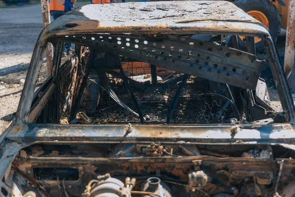 Kül ve çamur kaplı yanmış cesetlerde bükülmüş metal ve erimiş yapılar görülüyor. Arabanın içi mahvolmuş. Askeri çatışma ve bombardıman sonucu. Yıkılmış otopark.