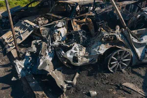 Kül ve çamur kaplı yanmış cesetlerde bükülmüş metal ve erimiş yapılar görülüyor. Arabanın içi mahvolmuş. Askeri çatışma ve bombardıman sonucu. Yıkılmış otopark.