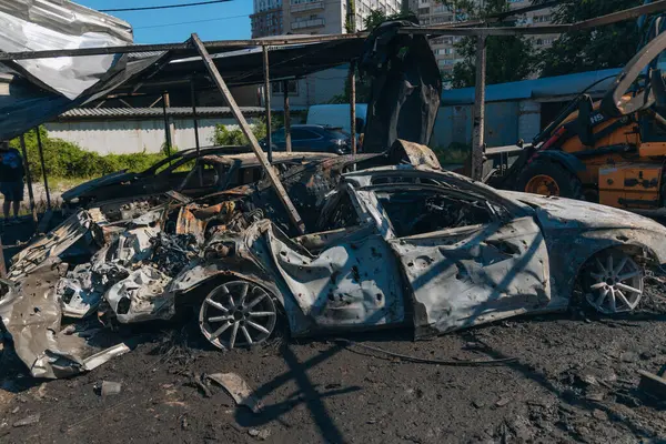 Kül ve çamur kaplı yanmış cesetlerde bükülmüş metal ve erimiş yapılar görülüyor. Arabanın içi mahvolmuş. Askeri çatışma ve bombardıman sonucu. Yıkılmış otopark.