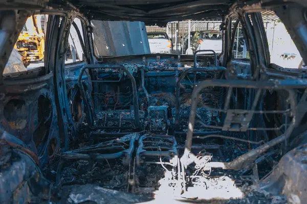 Kül ve çamur kaplı yanmış cesetlerde bükülmüş metal ve erimiş yapılar görülüyor. Arabanın içi mahvolmuş. Askeri çatışma ve bombardıman sonucu. Yıkılmış otopark.