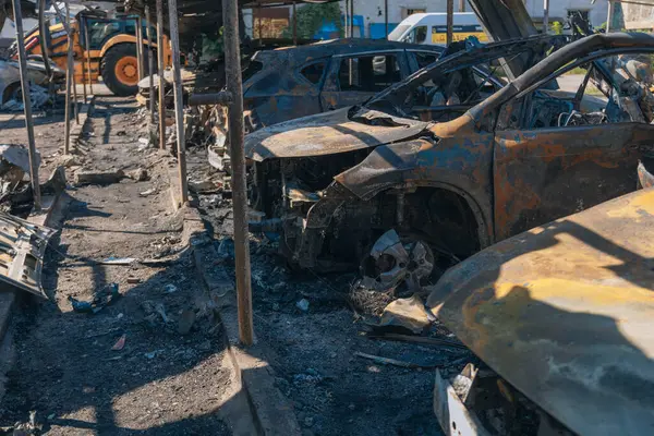 Kül ve çamur kaplı yanmış cesetlerde bükülmüş metal ve erimiş yapılar görülüyor. Arabanın içi mahvolmuş. Askeri çatışma ve bombardıman sonucu. Yıkılmış otopark.