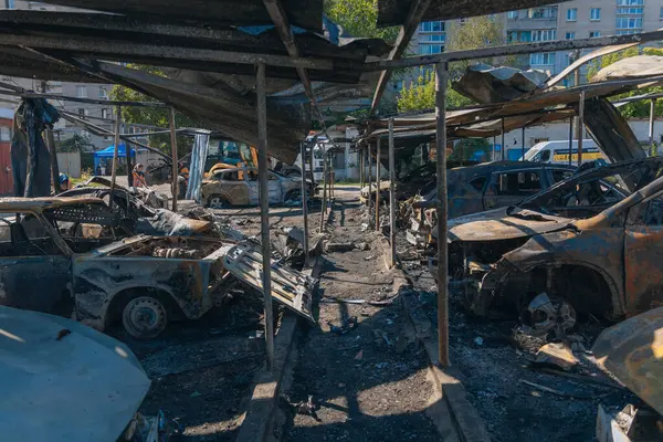 Kül ve çamur kaplı yanmış cesetlerde bükülmüş metal ve erimiş yapılar görülüyor. Arabanın içi mahvolmuş. Askeri çatışma ve bombardıman sonucu. Yıkılmış otopark.