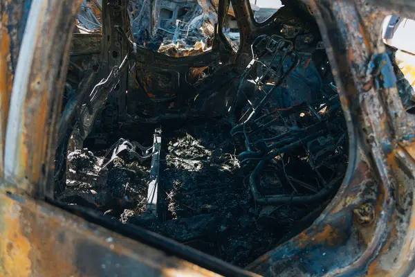 Kül ve çamur kaplı yanmış cesetlerde bükülmüş metal ve erimiş yapılar görülüyor. Arabanın içi mahvolmuş. Askeri çatışma ve bombardıman sonucu. Yıkılmış otopark.