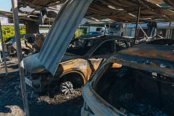 Kül ve çamur kaplı yanmış cesetlerde bükülmüş metal ve erimiş yapılar görülüyor. Arabanın içi mahvolmuş. Askeri çatışma ve bombardıman sonucu. Yıkılmış otopark.