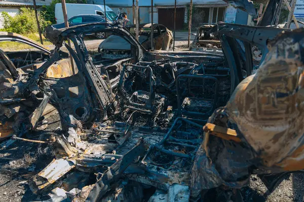 Kül ve çamur kaplı yanmış cesetlerde bükülmüş metal ve erimiş yapılar görülüyor. Arabanın içi mahvolmuş. Askeri çatışma ve bombardıman sonucu. Yıkılmış otopark.