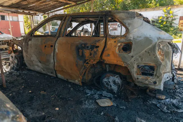 Kül ve çamur kaplı yanmış cesetlerde bükülmüş metal ve erimiş yapılar görülüyor. Arabanın içi mahvolmuş. Askeri çatışma ve bombardıman sonucu. Yıkılmış otopark.