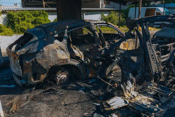 Kül ve çamur kaplı yanmış cesetlerde bükülmüş metal ve erimiş yapılar görülüyor. Arabanın içi mahvolmuş. Askeri çatışma ve bombardıman sonucu. Yıkılmış otopark.