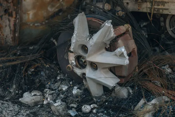 Kül ve çamur kaplı yanmış cesetlerde bükülmüş metal ve erimiş yapılar görülüyor. Arabanın içi mahvolmuş. Askeri çatışma ve bombardıman sonucu. Yıkılmış otopark.