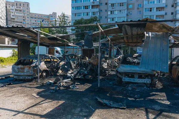 Kül ve çamur kaplı yanmış cesetlerde bükülmüş metal ve erimiş yapılar görülüyor. Arabanın içi mahvolmuş. Askeri çatışma ve bombardıman sonucu. Yıkılmış otopark.