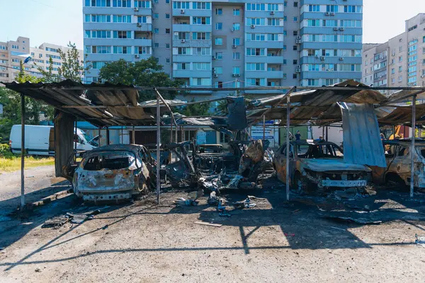 Kül ve çamur kaplı yanmış cesetlerde bükülmüş metal ve erimiş yapılar görülüyor. Arabanın içi mahvolmuş. Askeri çatışma ve bombardıman sonucu. Yıkılmış otopark.