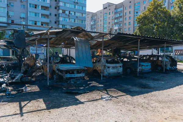 Kül ve çamur kaplı yanmış cesetlerde bükülmüş metal ve erimiş yapılar görülüyor. Arabanın içi mahvolmuş. Askeri çatışma ve bombardıman sonucu. Yıkılmış otopark.