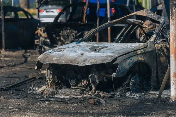 Kül ve çamur kaplı yanmış cesetlerde bükülmüş metal ve erimiş yapılar görülüyor. Arabanın içi mahvolmuş. Askeri çatışma ve bombardıman sonucu. Yıkılmış otopark.