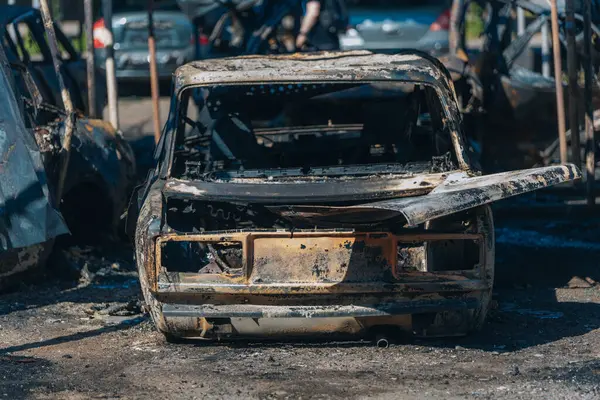 Kül ve çamur kaplı yanmış cesetlerde bükülmüş metal ve erimiş yapılar görülüyor. Arabanın içi mahvolmuş. Askeri çatışma ve bombardıman sonucu. Yıkılmış otopark.