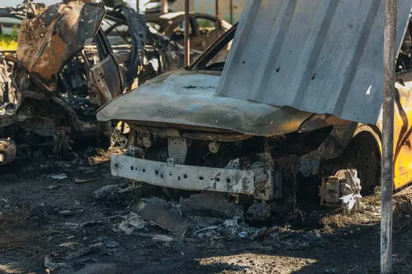 Kül ve çamur kaplı yanmış cesetlerde bükülmüş metal ve erimiş yapılar görülüyor. Arabanın içi mahvolmuş. Askeri çatışma ve bombardıman sonucu. Yıkılmış otopark.