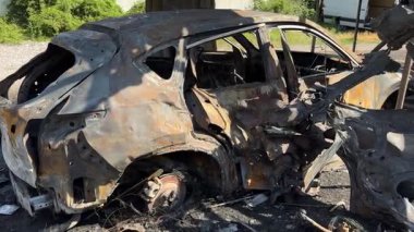 Kül ve çamur kaplı yanmış cesetlerde bükülmüş metal ve erimiş yapılar görülüyor. Arabanın içi mahvolmuş. Askeri çatışma ve bombardıman sonucu. Yıkılmış otopark.