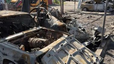 Kül ve çamur kaplı yanmış cesetlerde bükülmüş metal ve erimiş yapılar görülüyor. Arabanın içi mahvolmuş. Askeri çatışma ve bombardıman sonucu. Yıkılmış otopark.