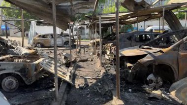 Kül ve çamur kaplı yanmış cesetlerde bükülmüş metal ve erimiş yapılar görülüyor. Arabanın içi mahvolmuş. Askeri çatışma ve bombardıman sonucu. Yıkılmış otopark.