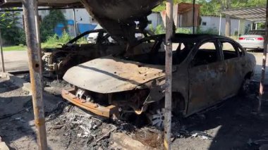 Kül ve çamur kaplı yanmış cesetlerde bükülmüş metal ve erimiş yapılar görülüyor. Arabanın içi mahvolmuş. Askeri çatışma ve bombardıman sonucu. Yıkılmış otopark.